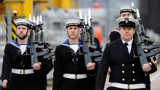Подводники стоят на внимании во время церемонии, чтобы официально сделать «Хитрый» заказанным военным кораблем Королевского флота