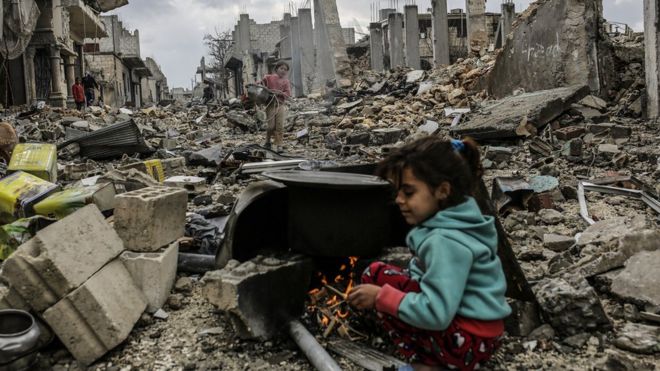 A Syrian girl hides in the ruins of the bombed out city of Kobabe