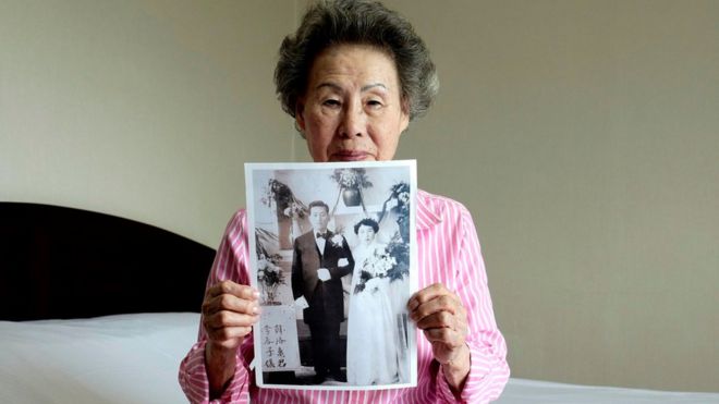 Lee Chun-ja, 88, holds up an old picture of her wedding in a hotel room (19 Aug 2018)