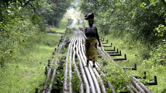 Женщина идет по нефтепроводу в Варри, Нигерия