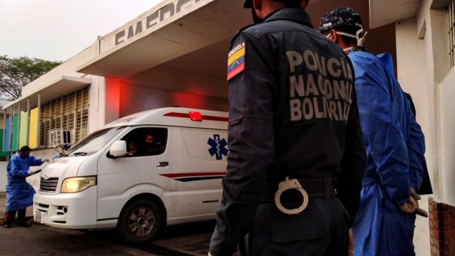 Healthcare workers and members of the Bolivarian national police watch as an ambulance arrives with prisoners outside a hospital after a riot erupted inside a prison in Guanare, Venezuela May 1, 2020.