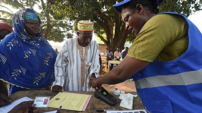 Чиновник Избирательной комиссии (ЕК) помогает избирателю выполнить биометрическую проверку, прежде чем отдать свой голос за президентские выборы в округе Боле в северной Гане 7 декабря 2016 года.