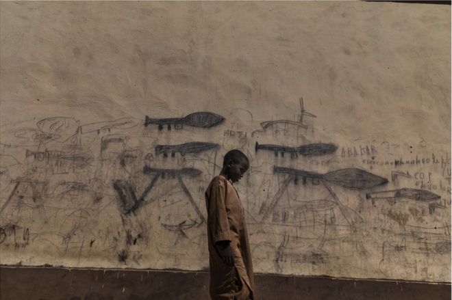 Ребенок стоит перед стеной, покрытой рисунками