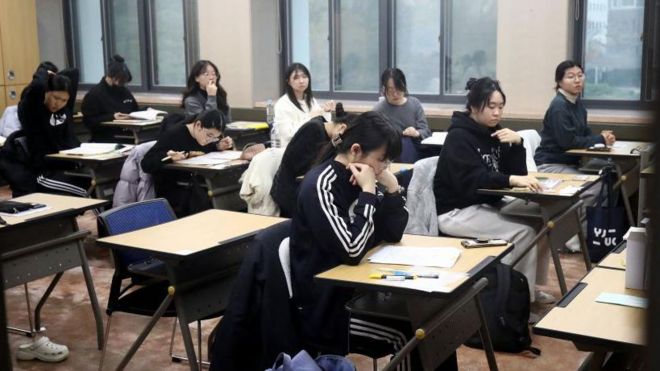 Estudiantes surcoreanos sentados en pupitres escolares. 