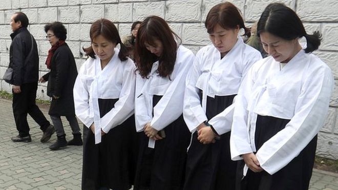Mujeres muestran sus respetos ante la estatua de una "mujer de confort" de Busán, Corea del Sur.