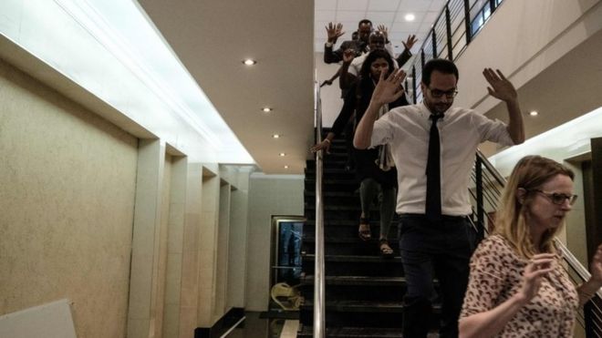 Varias personas bajan una escalera con los brazos arriba