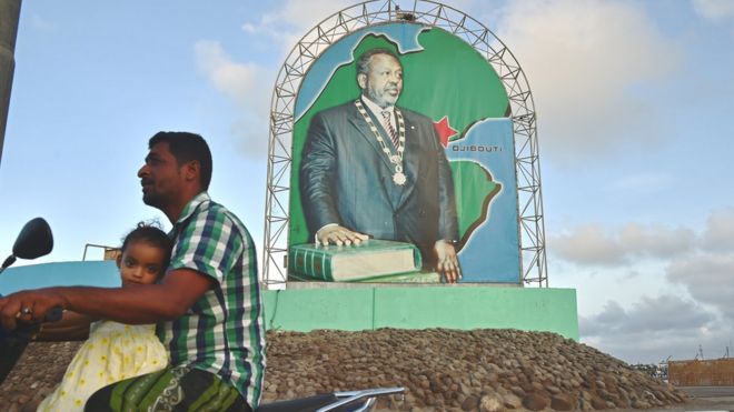 Мотоциклист проезжает мимо плаката Исмаила Омара Геллеха, президента Джибути в Джибути