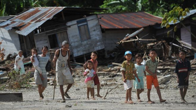 Penduduk Desa Tumalei di Pulau Mentawai berjalan di depan rumah mereka yang hancur pada 31 Oktober 2010, enam hari setelah gempa dengan skala 7,7 SR yang memicu tsunami di kawasan tersebut.