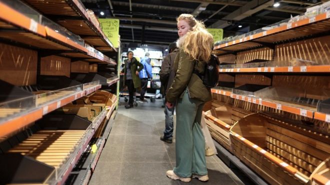 Una mujer mira los estantes de pan vacíos en un supermercado después de que se levantara el toque de queda.