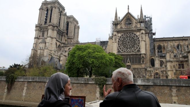 Una monja y un cura observan la catedral de Notre Dame el día después del incendio.