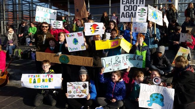 Школьники держат плакаты против изменения климата
