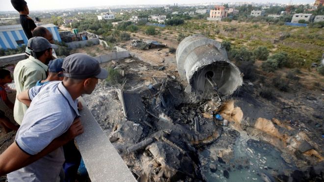 Палестинцы смотрят на ущерб, нанесенный израильскому воздушному удару на окраине города Газа (9 августа 2018 года)