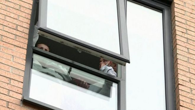 Двое студентов смотрят в окно своего жилья в Манчестерском столичном университете