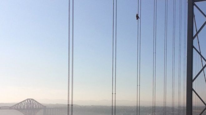 Un técnico trabajando a gran altura sobre un puente