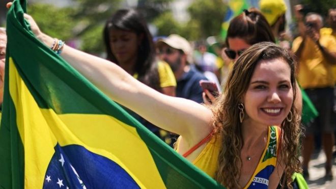Сторонник крайне правого кандидата в президенты Бразилии Джейра Болсонаро держит национальный флаг Бразилии.