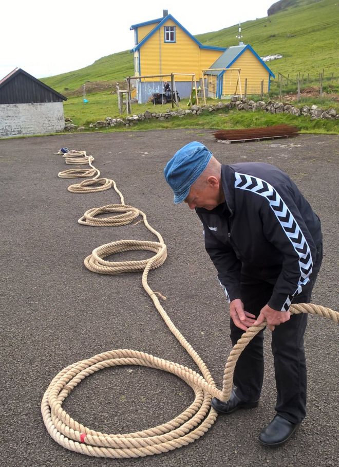 Оскар Йоэнсен выкладывает длинную веревку, необходимую для восхождения перед деревенской школой