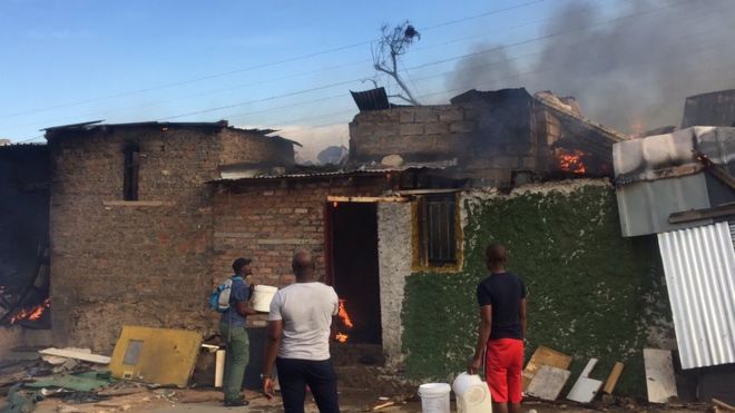 Жители стоят возле домов, разрушенных пожаром