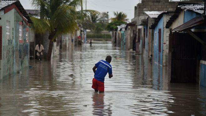 Port-au-Prince şəhərində kişi suyun içi ilə gəzməyə çalışır