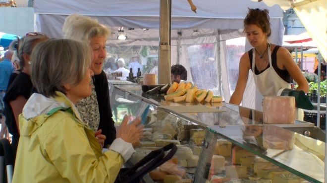 Занятый сырный ларек на фермерском рынке просматривается несколькими дамами