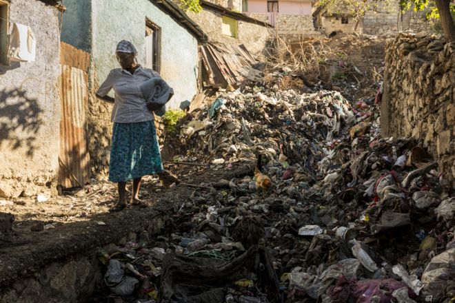 Женщина стоит перед мусором, смытым с горы