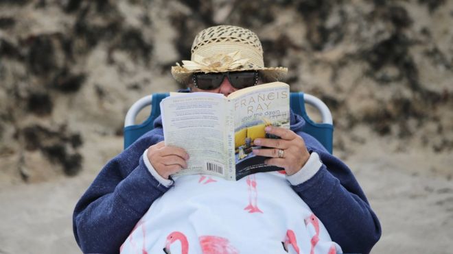 Человек на пляже читает книгу