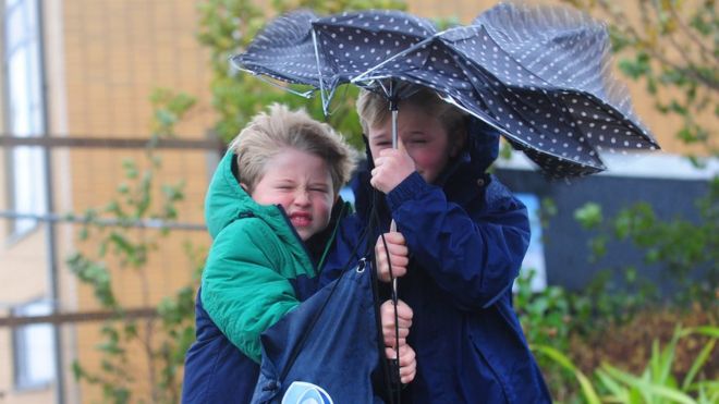 Два мальчика прячутся под сломанным зонтиком