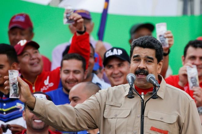 Президент Венесуэлы Николас Мадуро выставляет фиктивный законопроект на 100 боливаров с изображением президента Национального собрания Генри Рамоса Алапа во время проправительственного митинга в Каракасе, Венесуэла, 17 декабря 2016 года.