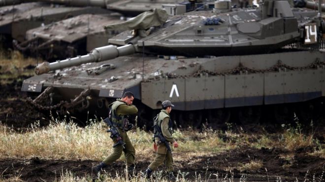 Израильские солдаты идут рядом с танками возле израильской стороны границы с Сирией на оккупированных Израилем Голанских высотах, Израиль, 9 мая 2018 года