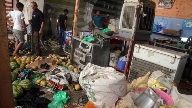 Иракцы осматривают место взрыва бомбы на открытом рынке в районе Шааб в северном Багдаде