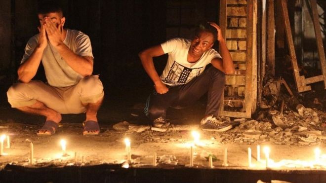 Люди зажигают свечи на месте взрыва в Карраде, чтобы помнить жертв