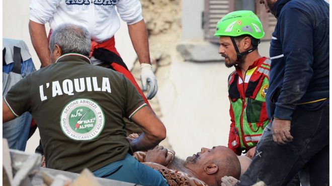 Спасатели оказывают помощь пострадавшему в землетрясении в центральной Италии