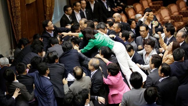 Японские законодатели окружают председателя комитета во время голосования 17 сентября 2015 года