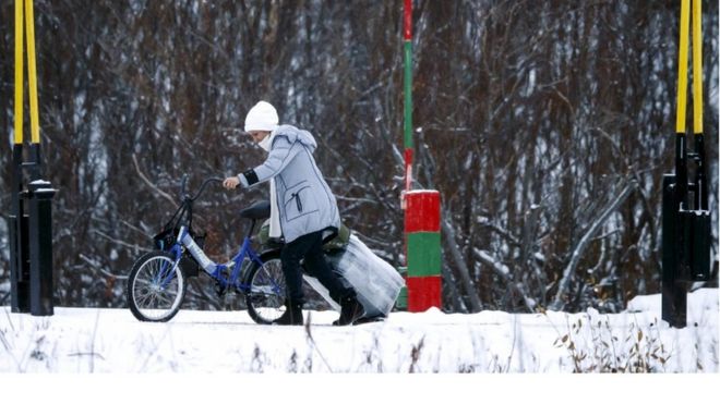 Мигрант с велосипедом и чемоданом пересекает границу между Норвегией и Россией в Стурскуге около Киркенеса в Северной Норвегии, 16 ноября 2015 года.