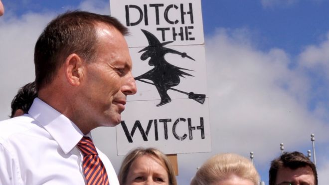 Тогдашний лидер оппозиции Австралии, Тони Эбботт, стоит перед табличкой с надписью «Уничтожить ведьму», которую держал протестующий в 2011 году.