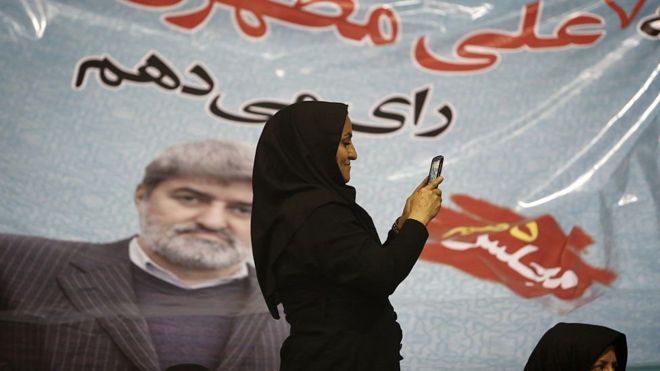 Иранская женщина фотографирует с помощью своего мобильного телефона перед портретом Али Мотахари, кандидата на предстоящих парламентских выборах, во время предвыборной встречи в Тегеране 23 февраля 2016 года