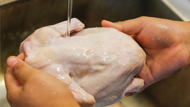 Persona lavando un pollo crudo