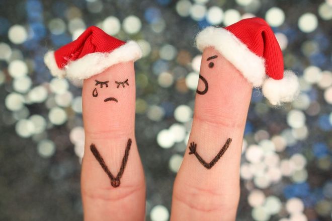 Concept photo: Fingers drawn and dressed up as man and woman with Santa hats, ready to celebrate Christmas. But instead they are quarrelling