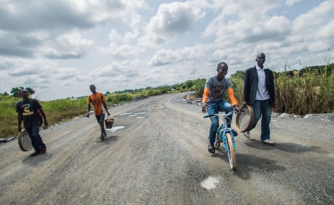 Группа мужчин гуляет и ездит на велосипеде по дороге со своим оборудованием