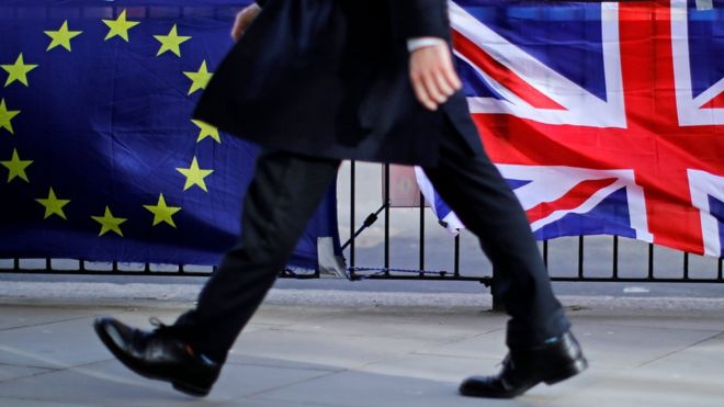 Мужчина идет перед флагами ЕС и Великобритании