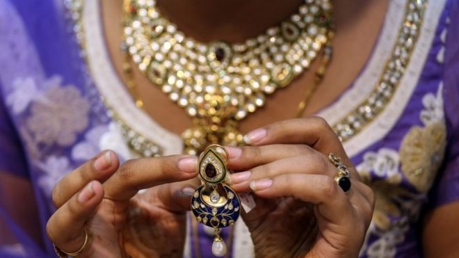 Индийская женщина проверяет золотые украшения в магазине по случаю фестиваля Dhanteras в Мумбаи, Индия, 09 ноября 2015 года