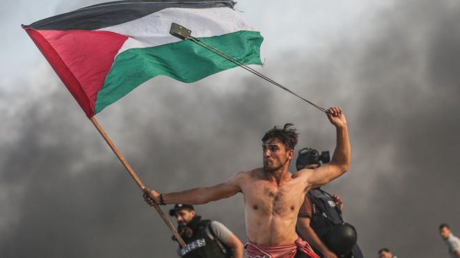 Палестинец держит флаг и качает слинг