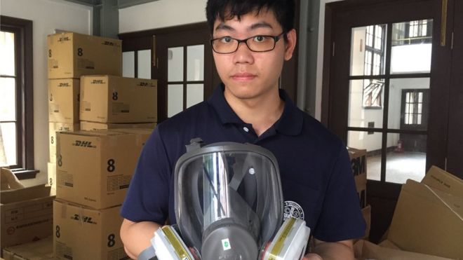 Alex Ko holding a gas mask in a church storage room