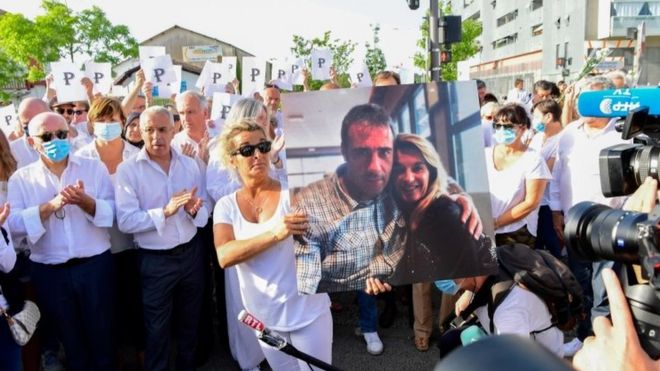 Mulher do motorista de ônibus Philippe Monguillot, Veronique Monguillot (centro) segura pôster com imagem do casal durante passeata em Bayonne, França. Foto: 8 de julho de 2020