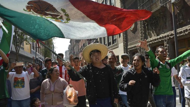 Южнокорейский мужчина машет мексиканским флагом на площади Сокало в Мехико