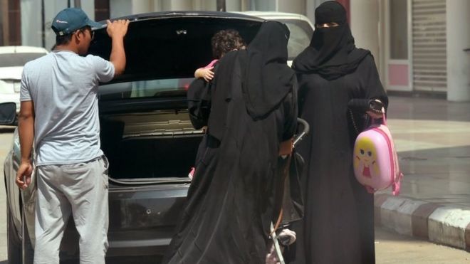 Саудовские женщины вынимают тележку для младенцев из багажника автомобиля возле торгового центра в столице Саудовской Аравии Эр-Рияде (27 сентября 2017 года)