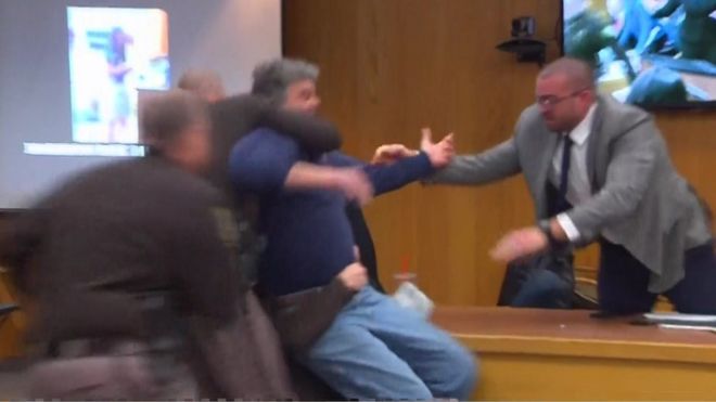 An angry father is restrained in court after lunging at paedophile doctor Larry Nassar