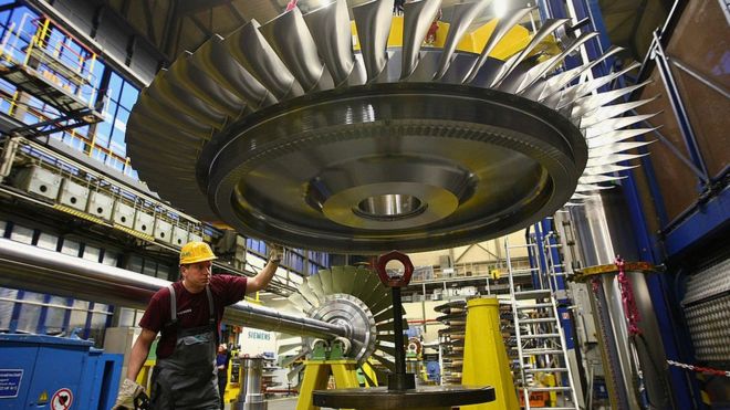 Рабочий использует пульт дистанционного управления для управления сборкой ротора турбины на газотурбинном заводе Siemens