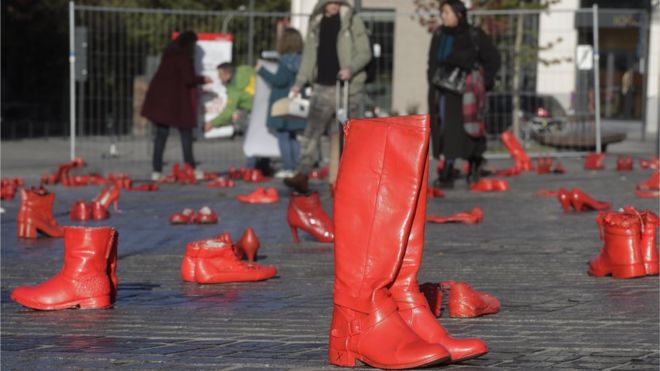Обувь, окрашенная в красный цвет, ставится на землю, чтобы символизировать жертв фемицида в рамках выставки, осуждающей все виды насилия в отношении женщин, на площади Журдан в Европейском районе Брюсселя, Бельгия, 25 ноября 2019 г.
