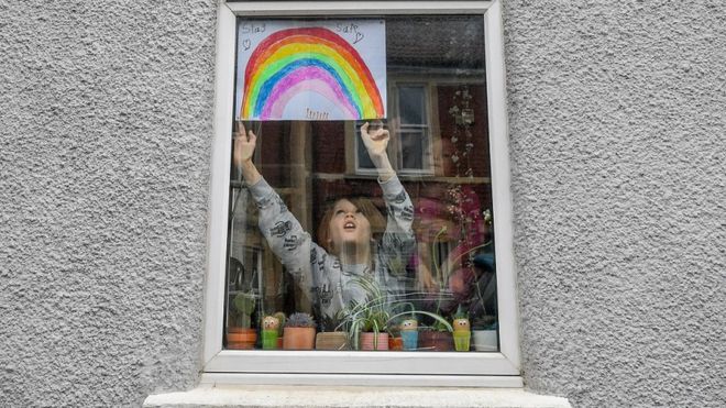 Ребенок кладет изображение радуги в окно