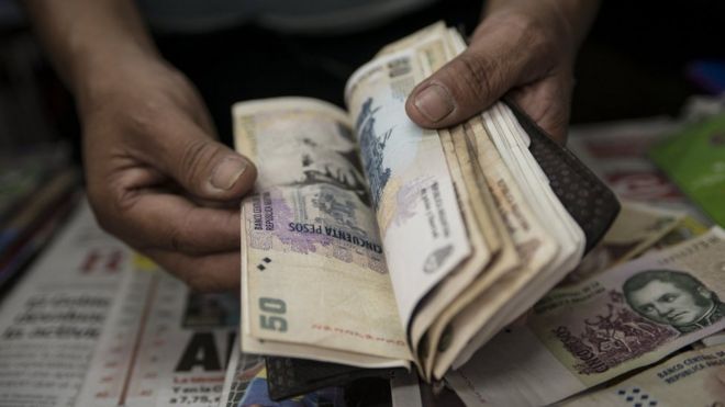 24 января 2014 года владелец газетного киоска считает счета в аргентинских песо в Буэнос-Айресе.